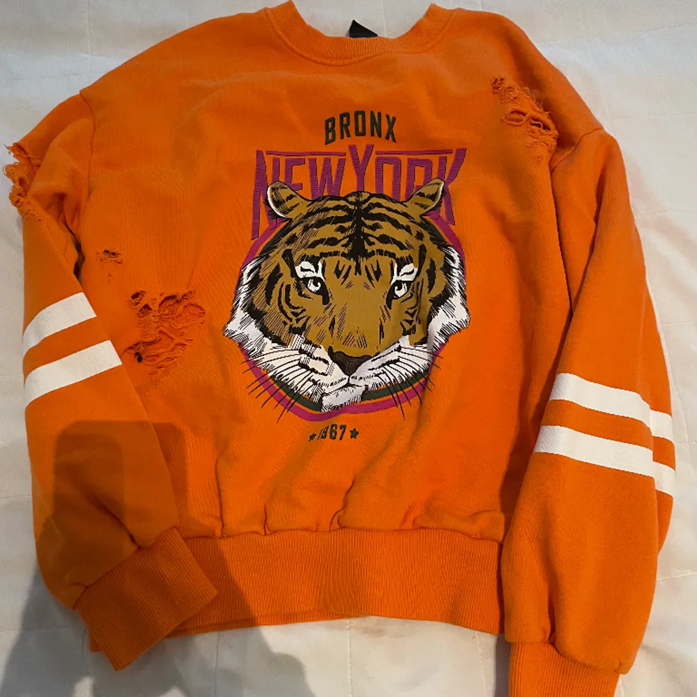 Jag säljer denna tjock tröja med new york motiv från Gina tricot. Den har tiger rivningar i tyget vilket inte är en defekt utan meningen.😊. Hoodies.