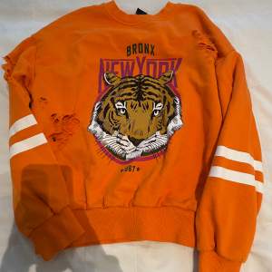 Jag säljer denna tjock tröja med new york motiv från Gina tricot. Den har tiger rivningar i tyget vilket inte är en defekt utan meningen.😊