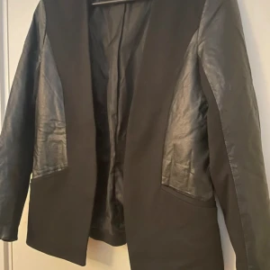 Kavaj  - Snygg kavaj med skinndetaljer. Använd ett fåtal gånger och är i ett bra skick. 