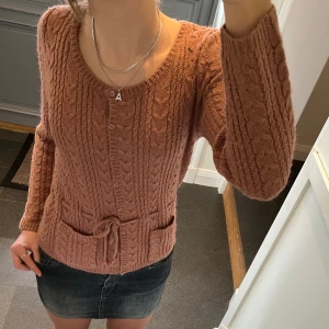 Rosa/brun stickad kofta  - Rosa/brun stickad kofta med snörning från H&M. Storlek S. Fint skick. Säljer även kjolen! Använd gärna köp nu! 