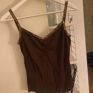 Linne - Brunt linne med paljett-detaljer, samt detaljer vid brösten. Superfint skick. Köpt second hand.