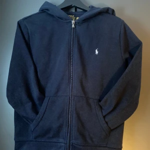 Ralph Lauren fleece full-zip Hoodie - Säljer en marinblå Ralph Lauren fleece full-zip Hoodie i storlek 14-16/(160). Säljes pga för liten! Använd fåtal gånger! Nypris 1095kr mitt pris 399kr
