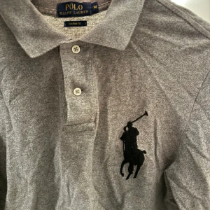 Ralph Lauren Tröja - Tröja från Ralph Lauren med stor brodering. Storlek M true to size. Använts mycket förr men fortfarande i bra skick idag. Har extra detaljer i längst ner som visas på bilden. 