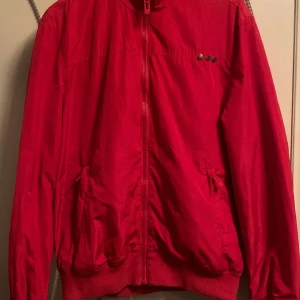 Röd vindjacka  - Lätt och smidig höst/vår jacka. Skyddar mot vind men är luftig och sval. Najs fit, lite croppad men ändå halvt oversized. 