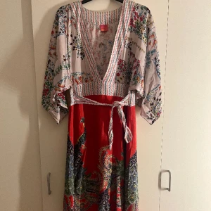 BY LYSGAARD mönstring klänning! - En mycket färgglad klänning med fåglar och blommor med en fin v-ringning!  Den är i storlek xs med stora armar och snörning vid midjan😃 Köparen står för frakten 📦📦