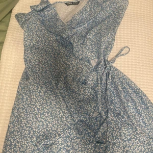 Blå klänning med vita blommor  - Jättebra skick. Använd endast ett par gånger. Normal i storlek. 