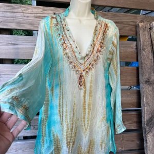Så fin tunika/blus i siden stl M-L - Fantastik fin tunika/blus/strandklänning i boho/hippie stil, batik mönstrad och vackra broderier/paljetter. Står ingen stl men jag uppskattar den till 36-40. Super skön tunn siden, så luftig och skön.