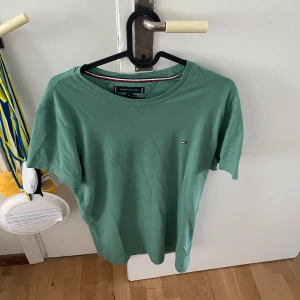 T-shirt: ”Tommy Hilfiger” - Tröja av märket ”Tommy Hilfiger” säljes, med bakgrund till för liten storlek. Färgen på tröjan är grön och lämpas sålunda utmärkt till det ljuvliga, somriga vädret.  Tröjan är sparsamt använd och i gott skick, så gott som ny.  Storlek: M  Pris 200kr