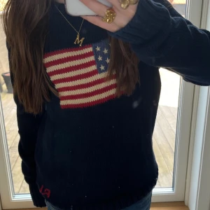 Polo Ralph lauren flag tröja  - Jätte fin polo Ralph lauren crew neck flag tröja! Köpt på Nk i Stockholm för 2000kr ungefär 2 månader sen, den var fel storlek därför säljer jag. Str 14-16 år. Skicka gärna prisförslag 💕