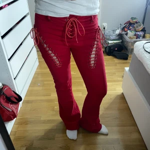 Röda lågmidjade jeans  - Super coola röda jeans med knytning från EDIKTED! Super bra skick bara använda ett fåtal gånger. Storlek M men passar även S