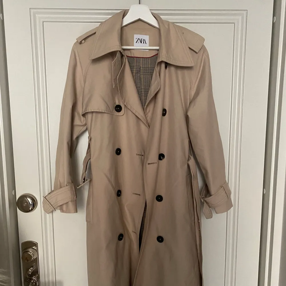 Jättesnygg och klassisk trenchcoat / kappa från Zara, perfekt nu till våren!   Utmärkt skick. Finns på Zara nu för 859 kr.   Jag är 177 cm lång på bilden. Skulle säga att den sitter som en normal 36. . Jackor.