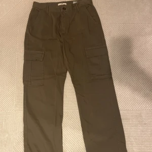 Cargo byxor - Ett par militärgröna cargos som är köpta på stradivarius. Storlek 44 men sitter lite små i storleken så det skulle passa som en 42/44. Har ej används, helt ny 🤍
