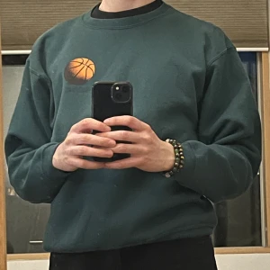 Snygg Sweatshirt med tryck - Snygg grön tjocktröja med basketinspirerade tryck 80% ull kommer hålla dig varm!  Modellen är 177cm och 65kg och tröjan passar perfekt Ursprungligen köpt för 600kr och i mycket bra skick! 