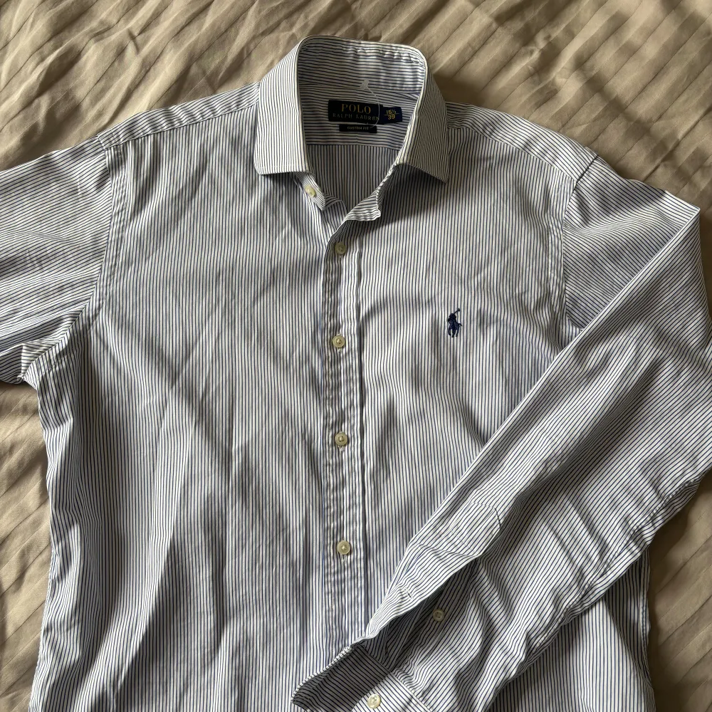 Ljus blå randig Ralph Lauren skjorta i storlek 39. Bra skick med ett väldigt litet hål på underärmen. Skjortor.