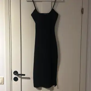 Ribbad svart klänning med slits. Slutar precis nedanför knäet