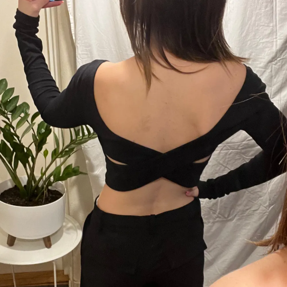 Black long sleeved crop top with cross cutouts on back. Toppar.