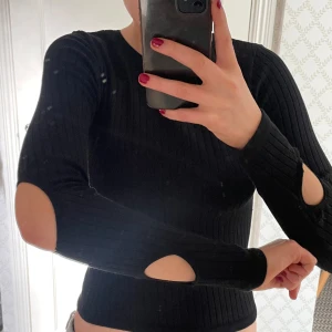 Svart långärmad tröja med detaljer på armarna - Säljer denna svarta tighta tröja från zara med coola hål på armarna. Stl S   Sparsamt använd och inga defekter förekommer 