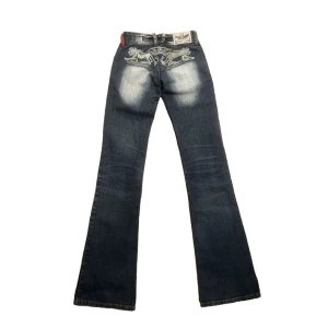 Crazy Age Jeans - jättefina y2k jeans från märket crazy age😍 passar low waist och bootcut me trampstamp🌠🌠 inga större defekter vad jag märkt förutom att några rhinestones tyvärr ramlat från trycket där bak😔🗽 mått i dm!🧶🧶 följ gärna för ja lägger upp mycke liknande🌟💛
