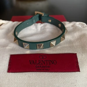 Valentino armband - Hej, säljer mitt valentino armband då jag inte använder det längre. Längd 22cm, bredd 1cm, färg mörkgrön, fint skick med få tecken på användning, utan repor eller jack. Allt orgninal medföljer inklusive extra nitar. Hör av er vid fler frågor!