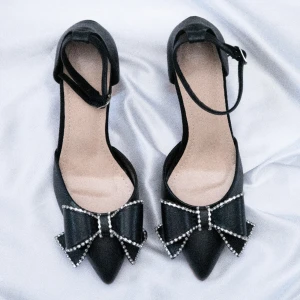 Stiletto Klackskor Med Rosett Dekoration   - Säljer dessa svarta klackskor med spetsig tå och vacker rosettdekor då dom är för stora för mig. Skorna är tillverkade av PU läder och klackhöjden är 7,5 cm. Fotlängd: 23,5 cm. Aldrig använda & skickas i original förpackningen.
