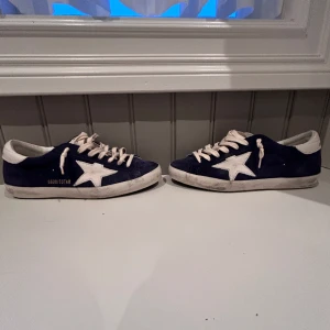Golden goose - Hej säljer ett par jätte eftertraktade golden goose i storlek 40🙌 de är i en mörkblå färg. Allt og medföljer! De är köpte på CETTIRE. Kvitto finns🔥 hör gärna av er om ni har frågor😊skicket är 10/10 helt nya. 