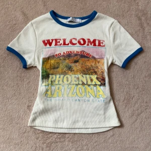 T-shirt med logo - Vit t-shirt med logo, oanvänd, tajt men töjbar, strl XS.