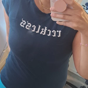 Mörkblå t-shirt med text - En mörkblå t-shirt med korta ärmar och texten 'reckless' tryckt i vitt på framsidan. T-shirten har en rund halsringning och är tillverkad i ett bekvämt material.  Anvgänd bara 1 gäng. 