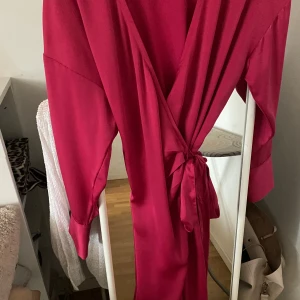 Rosa Klänning  - Elegant satin mörk rosa klänning. Super snygg på och passar flera storlekar då man kan justera det. Köptes för 600kr och är i nyskick