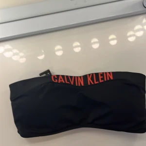 Bikini överdel  - Bikini överdel från Calvin Klein swimwear, oanvänd och i bra skick. Den har padding som går att ta bort. Texten på bikiniöverdelen ser mer rosa ut i verkligheten.