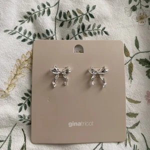 Silvriga rosettörhängen - Säljer ett par superfina oanvända silvriga rosettörhängen från Gina!🥰