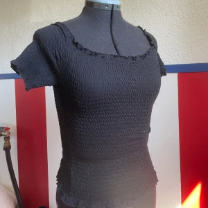 Stretchig topp - Stretchig svart topp. Ärmarna går att ha både upp på axlarna och off shoulder.  Går att ha bara för sig, men också perfekt för att ha under en korsett.