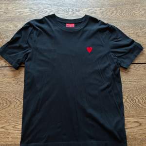 En svart Hugo boss t-shirt med en hjärta på framsidan och texten ”Hugo” på baksidan. Tröjan är mycket sparsamt använd och i väldigt fint skick. Storlek medium.