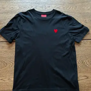 En svart Hugo boss t-shirt med en hjärta på framsidan och texten ”Hugo” på baksidan. Tröjan är mycket sparsamt använd och i väldigt fint skick. Storlek medium.