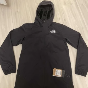 The North Face vind/regn-jacka  - En vind/regn-jacka som är oanvänd och köpt i år med prislappen kvar på 850 kr. Storlek 170 och köpt från deras egna hemsida. Priset går att diskuteras!