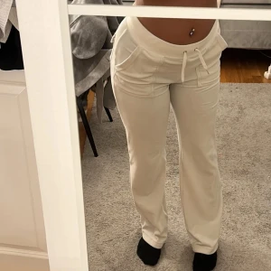 Beige mjukisbyxor - Ett par beige mjukisbyxor med låg midja och snörning i midjan. Byxorna har fickor fram och bak, och är tillverkade i ett mjukt och bekvämt material. juicy couture