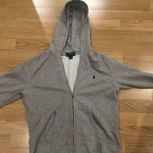 Grå Ralph lauren zip - Trendig grå Ralph lauren zip up, skick 7/10 ett litet hål som knappt syns vid ärmen. Storlek L i barnstorlek sitter som xs. Priset kan diskuteras.