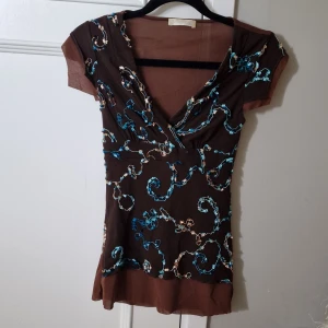 Toksnygg topp - Använd men inga skador eller blekningar. Oerhört stretchig och snygg över bysten. I stretch/nät/broderier. Bsksidan genomskinlig och framsidan sytt med vackra broderier i turkos. Otroligt snygg till jeans Inköpt i Milano.