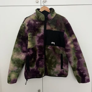 Stüssy Reversable Tie-Dye Micro-Fleece Jacket - Storlek L. TTS.  I väldigt fint skick, utöver ett pyttelitet hål i en av armveckens, syns inte alls när man har på sig jackan.