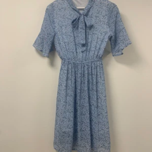 blommig klänning - blommig klänning med knytning i halsen, supergullig och modest, går ungefär till knäna på mig som är 172 jätteflowy material med supersöta små vita blommor på