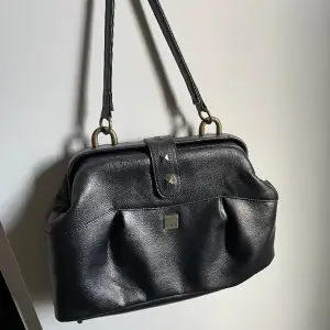 En ”axel” väska köpt second hand i vintage stil från märket fny.