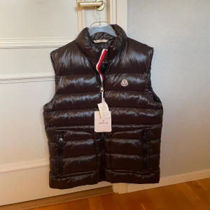 Moncler Väst - Svart - 🚨STEAL!🚨 Vill sälja snabbt! Svart Moncler väst. Köpt på Farfetch för 480 euro + frakt. Prislapp finns kvar. Storlek: 6 vilket motsvarar L/XL. Skick:10/10, aldrig använd. Tveka inte på att kontakta oss för fler bilder eller info!🙌
