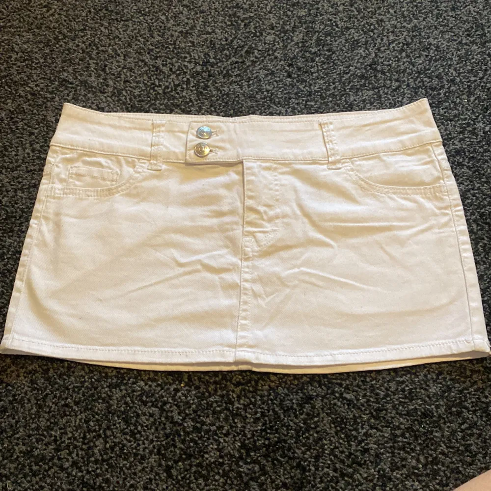 vit lågmidjad mini jeanskjol med 2 knappar i strl 38 <3 midjemått rakt av - 41 cm längd -29 cm . Kjolar.