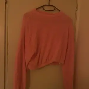En rosa stickad tröja som är väldigt mjuk i materialet. Något kortare i längden och i mycket bra skick. Liten i storleken.