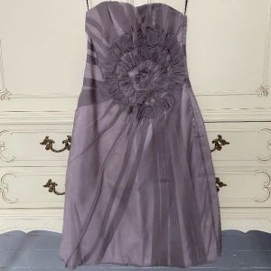 Fin lila/grå festklänning - Superfin lila/grå knälång festklänning med stor blomma insytt i midjan utan axelband. Den är verkligen superfin på. Skicka meddelande för fler bilder. Använd 1 gång. Nypris 999 kr på Zara. 