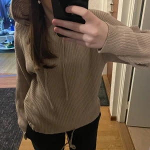 Stickad tröja med luva - Beige stickad tröja med luva, justerbar nertill. Helt oanvänd, prislappen finns kvar!