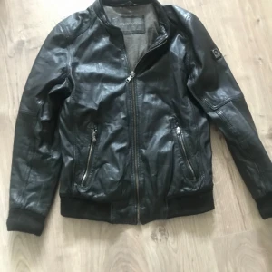Skinnjacka från oakwood - I bra skick förutom ett hål i ena fickan inget som syns och tyvärr har jag råkat tappat bort luvan vid flytt. Köpt för ca:2500 mitt pris är: 100 .Fler bilder kan absolut skickas vid intresse.