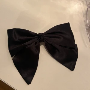 Svart stor satin rosett  - Rosett för att ha i håret med klämma, aldrig använd. Har 2 därav säljer jag denna 