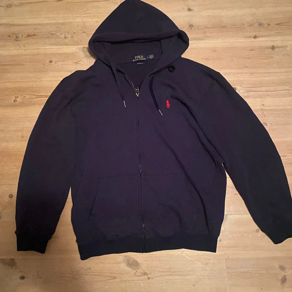 Ralph lauren zip hoodie i mörkblå färg. Storleken är large. Tröjan är i bra skick förutom fläcken på bild 3 syns dock ej mycket vid användning och går säkert att ta bort därav priset . Hoodies.