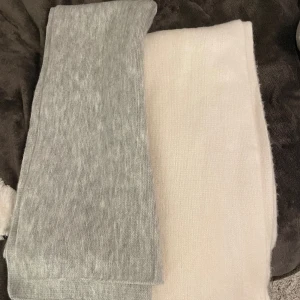 Halsdukar - Två halsdukar en i ljusgrått och den andra i vitt🫶🏻mjukt material!! Jättefint skick knappt använda! Säljer helst båda tillsammans:)