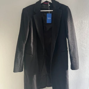 Svart kappa - Snygg svart kappa, lite tunnare material så perfekt nu till våren!🖤Strl XS, aldrig använd men köpt på Sellpy. Har ett hål på innertyget, se bild